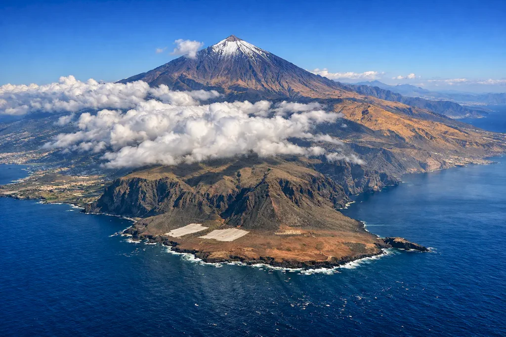 Вид на Тенерифе с воздуха: вулкан Тейде, зеленые северные склоны, засушливое южное побережье, Атлантический океан.